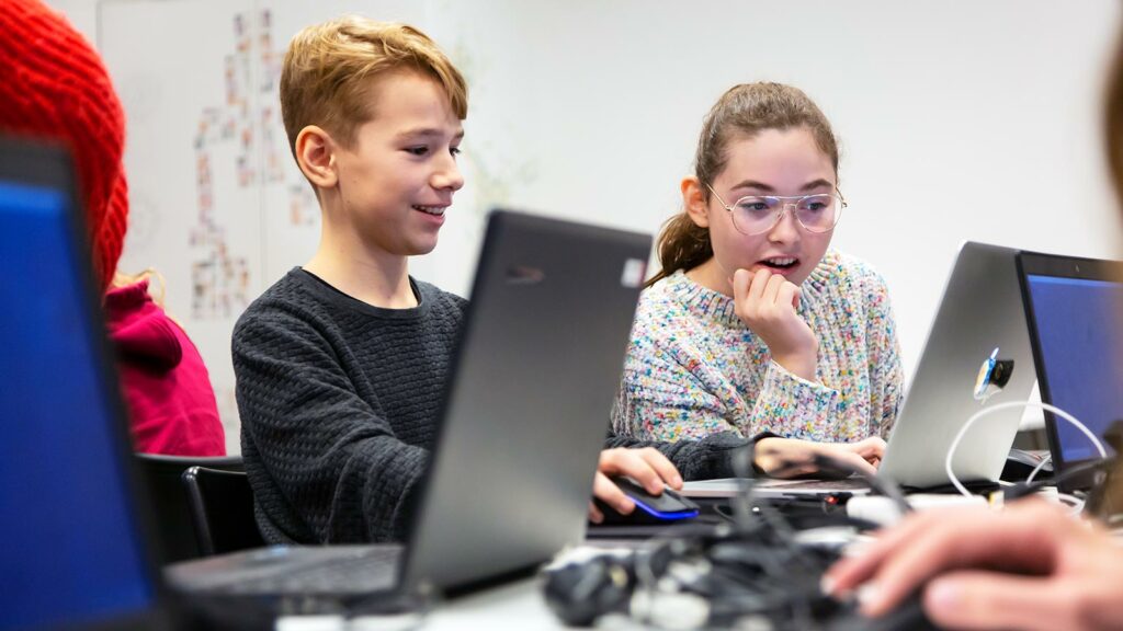 tjej och kille som sitter framför datorn och programmerar