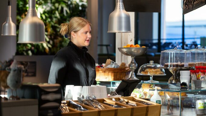 tjej som står vid disken och tar emot beställning i restaurangen.