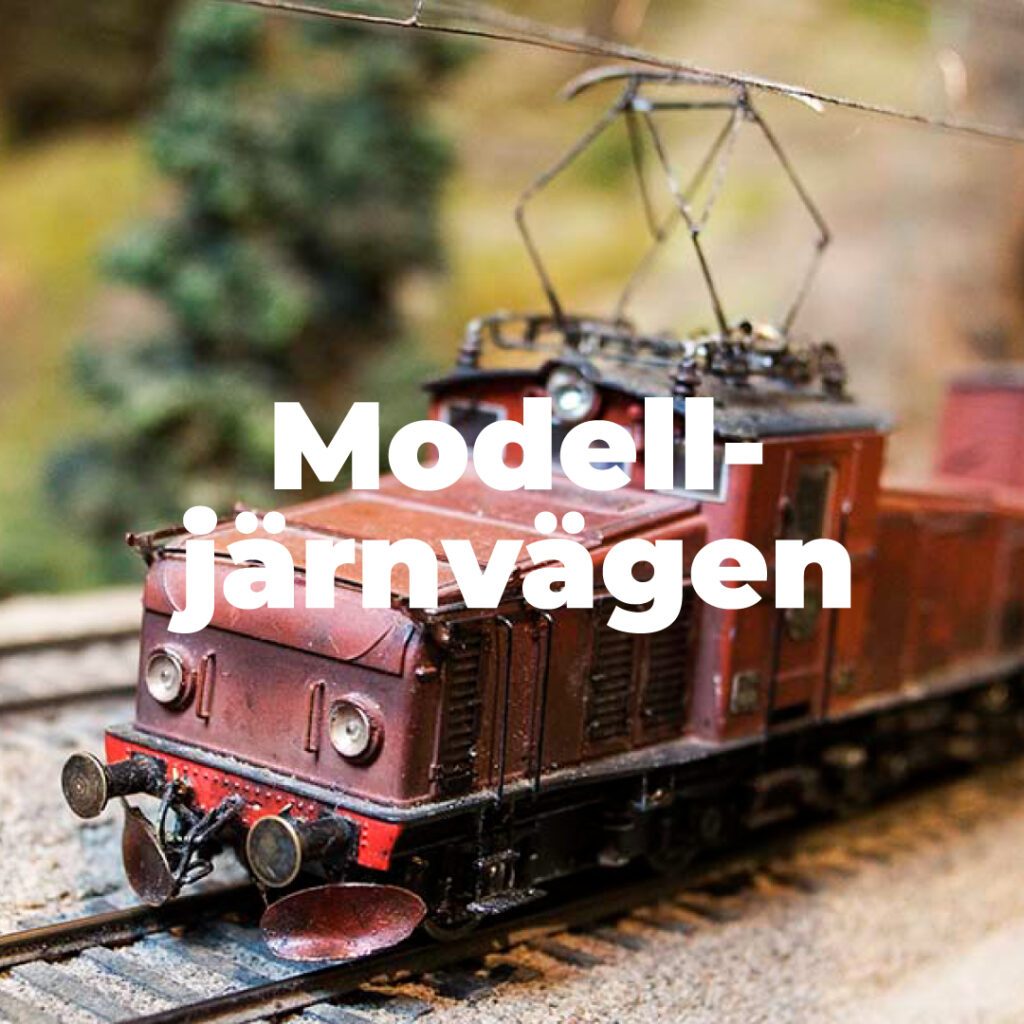 Ett rött litet tågmodell gjort av trä med texten modelljärnvägen